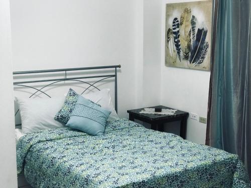 a bedroom with a bed with a blue comforter at HCEAS villa is 5 min fr. airport & to the beaches in Bon Accord