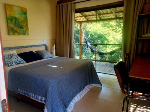 um quarto com uma cama e uma grande janela em Suítes Manjuba Praia de Sta Tereza em Ilhabela