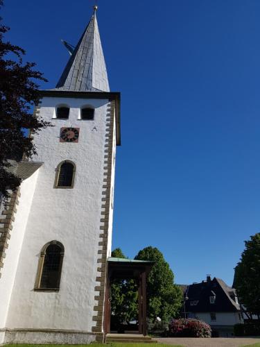 a white tower with a steeple with a clock on it at Pilgrims "Frieda" gemütlich Wohnen mit 2 Schlafzimmern in Meschede