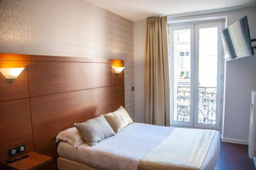 a hotel room with a bed and a window at The Originals City, Hôtel Bristol, Le Puy-en-Velay in Le Puy-en-Velay