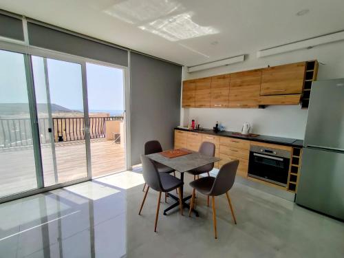 kuchnia ze stołem i krzesłami oraz duże okno w obiekcie Panoramic Penthouse Haven w mieście Mellieħa