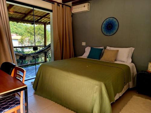 um quarto com uma cama verde e uma varanda em Suítes Manjuba Praia de Sta Tereza em Ilhabela