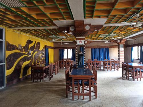 una sala da pranzo con tavoli e sedie e un dipinto sul muro di Hotel Aane a Itānagar