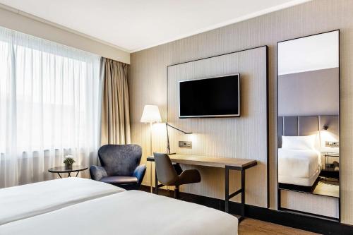 a hotel room with a bed and a desk at NH Brussels Airport in Diegem