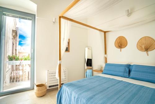 a bedroom with a blue bed and a large window at Marianna 25 in Polignano a Mare