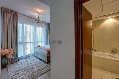 - une chambre avec un lit et une baignoire à côté d'une fenêtre dans l'établissement Durrani Homes - Luxe Living with Burj Khalifa and Fountain View - third room without partition, à Dubaï