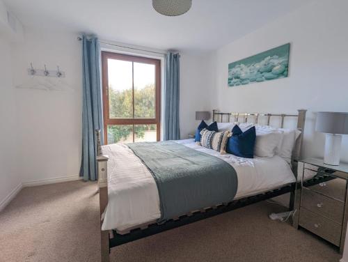 a bedroom with a bed with blue curtains and a window at Brooklands Central Apartment in Newcastle