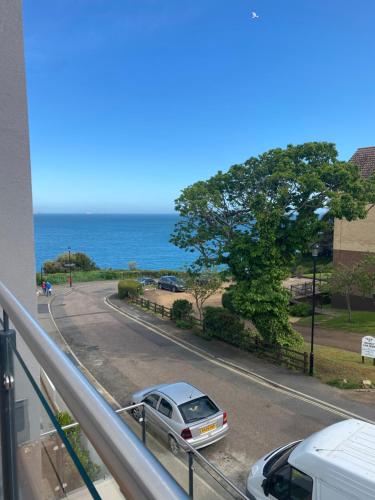 a car parked on a road next to the ocean at The Bay house Apartments , shanklin in Shanklin