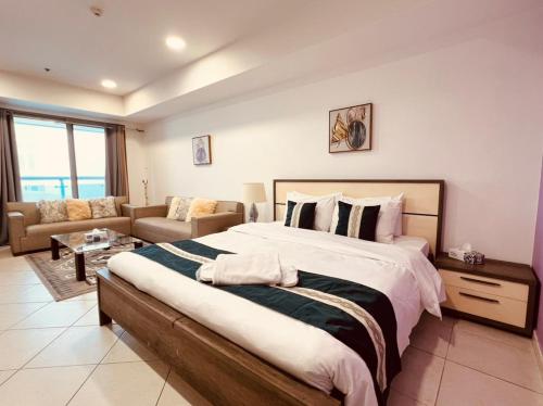 a bedroom with a large bed and a living room at 3 Bedroom Sea view Apartment princess marina ! WALK TO BEACH in Dubai