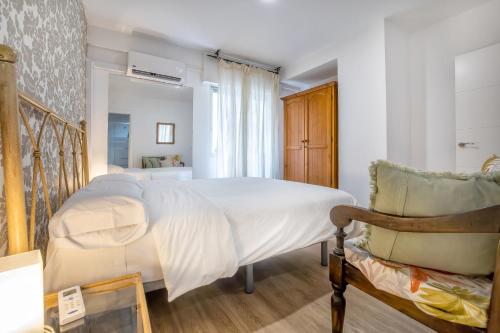 - une chambre avec un lit blanc et une chaise dans l'établissement Apartamento Centro Cordoba & Parking Gratuito, à Cordoue
