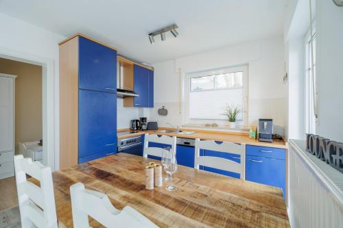 a kitchen with blue cabinets and a wooden table at Boddenkieker 12 in Zingst