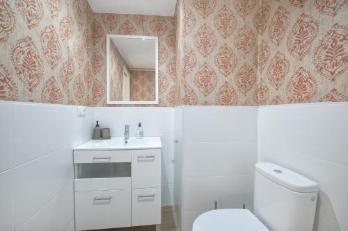 La salle de bains blanche est pourvue de toilettes et d'un miroir. dans l'établissement Apartamento Centro Cordoba & Parking Gratuito, à Cordoue