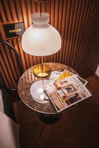 a table with a lamp and a magazine on it at Genova Centro - Lussuosa Suite Arte e Storia in Genova