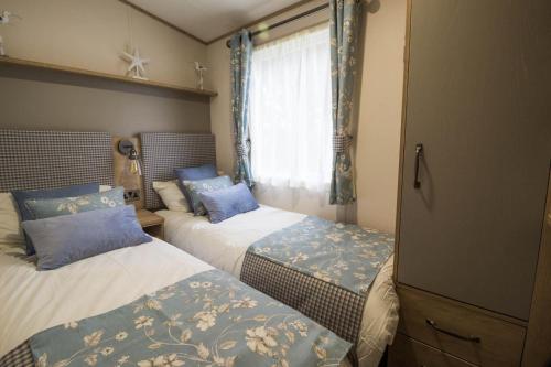 een slaapkamer met 2 bedden en een raam bij Lovely 6 Berth Caravan With Wi-fi At Weeley Bridge In Essex Ref 69015r in Weeley