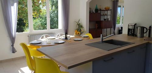 a kitchen with a wooden counter top and yellow chairs at Superb contemporary 2 bed villa +private pool in Cancon