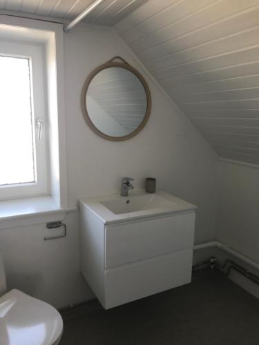 uma casa de banho branca com um lavatório e um espelho em Seaside Top em Thisted