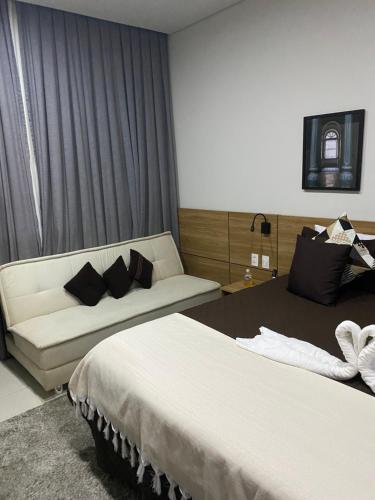 une chambre d'hôtel avec deux lits et un canapé dans l'établissement LOFT CENTRAL de ITAIPAVA - GRANJA BRASIL, à Itaipava