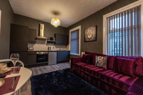 a living room with a red couch and a kitchen at Regent Road by the V Group in Blackpool