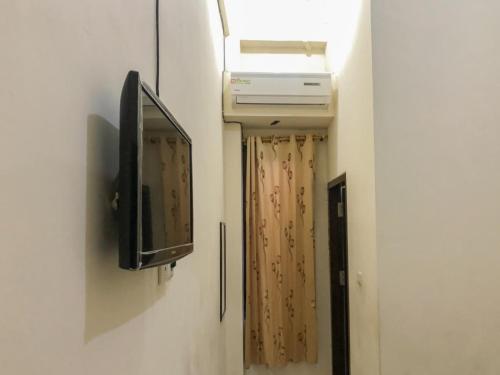 a television attached to a wall with a window at Hotel Lido 88 Sorong Mitra RedDoorz in Sorong