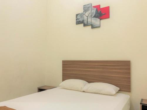 a bed in a room with two pictures on the wall at Hotel Lido 88 Sorong Mitra RedDoorz in Sorong