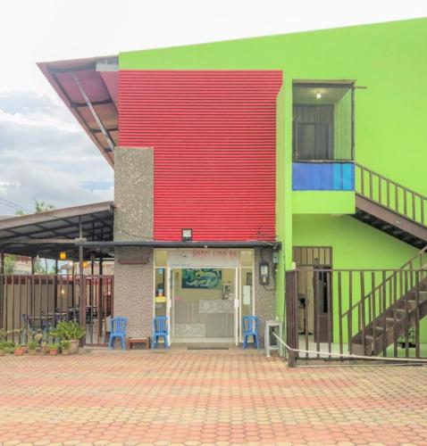 a building with a red and green facade with blue chairs at Hotel Lido 88 Sorong Mitra RedDoorz in Sorong