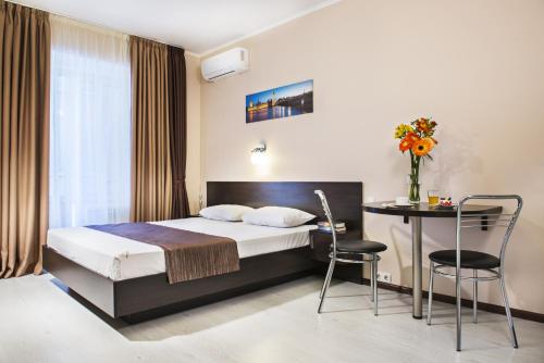 um quarto de hotel com uma cama, uma mesa e cadeiras em Flatlux Apartments em Kiev