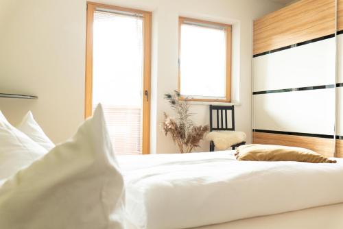 a bedroom with a white bed and two windows at Astegg, Apart in Finkenberg