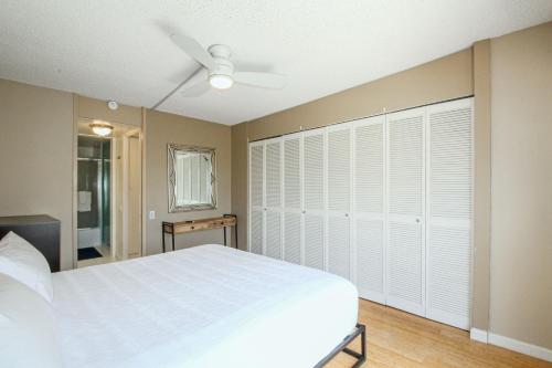Schlafzimmer mit einem großen weißen Bett und einem Deckenventilator in der Unterkunft Mid Century Modern Tropical Getaway 30 plus night rental in Honolulu