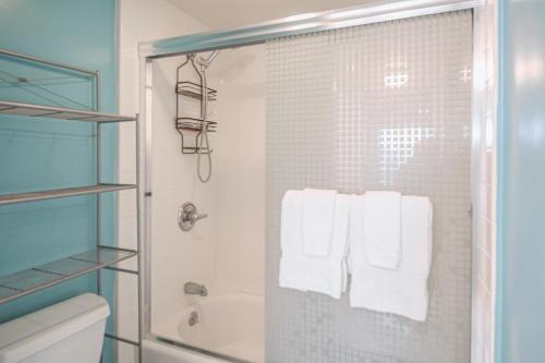 ein Bad mit einer Dusche, einem WC und Handtüchern in der Unterkunft Mid Century Modern Tropical Getaway 30 plus night rental in Honolulu