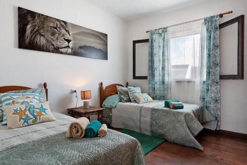 a bedroom with two beds and a lion picture on the wall at Casa Luz Elena in Puerto del Carmen