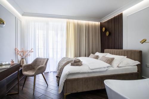 a bedroom with a bed and a chair and a window at Luksusowy Apartament Przy Filharmonii in Katowice