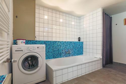 a bathroom with a tub and a washing machine at Apartments im Einhornhaus in Lübeck