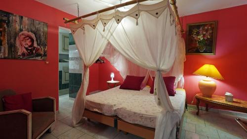 a bedroom with a canopy bed with red walls at Grand Kaz'Amour - 3 étoiles in Bouillante