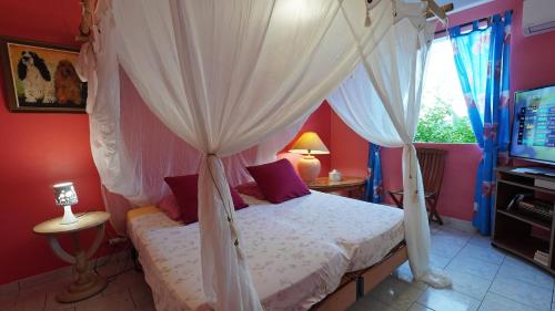 a bedroom with a canopy bed and a television at Grand Kaz'Amour - 3 étoiles in Bouillante