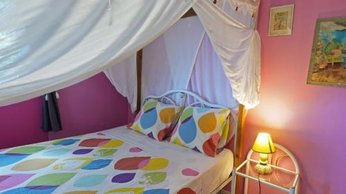 a bedroom with a bed with a canopy and a lamp at Grand Kaz'Amour - 3 étoiles in Bouillante