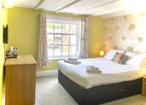 1 dormitorio con 1 cama con toallas en The Pier Inn, en Whitby