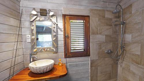uma casa de banho com um lavatório e um espelho em Grand Kaz'Amour - 3 étoiles em Bouillante