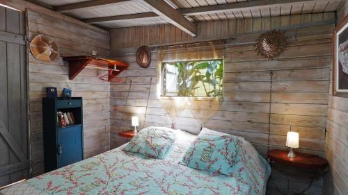 um quarto com uma cama numa parede de madeira em Grand Kaz'Amour - 3 étoiles em Bouillante