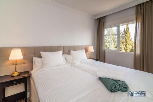 - une chambre avec un grand lit blanc et une fenêtre dans l'établissement Sunlit 2 BDRM Apt with View in Centro Plaza, à Marbella