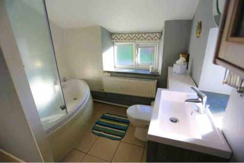 a bathroom with a tub and a toilet and a sink at Ashdale Cottage cosy 4 bedroom holiday home near Amroth in Pembrokeshire