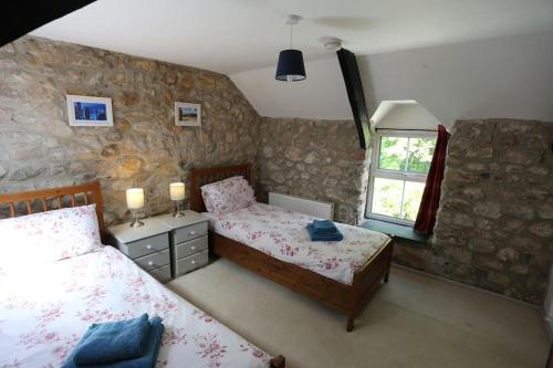1 dormitorio con 2 camas y ventana en Ashdale Cottage cosy 4 bedroom holiday home near Amroth, en Pembrokeshire