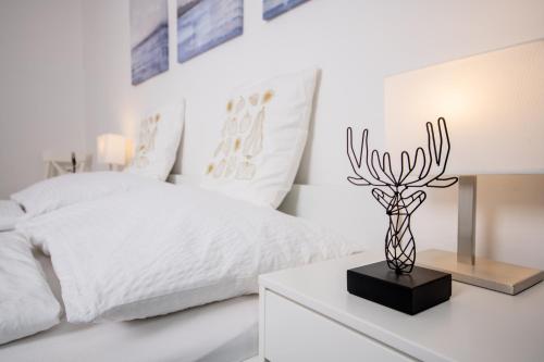 a white bedroom with a bed and a vase on a table at atrium roselina in Kirchstetten