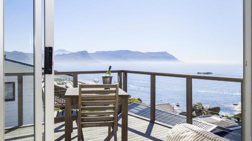 uma varanda com uma mesa e vista para o oceano em Penguins View Guesthouse em Simonʼs Town