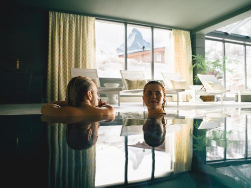 two women are standing in a swimming pool at BEAUSiTE Zermatt in Zermatt