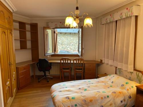 een slaapkamer met een bed, een bureau en een raam bij Casa Conchita de Benasque in Benasque