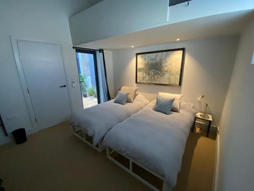 una camera con due letti con lenzuola bianche e una finestra di May Road, stylish townhouse a Twickenham