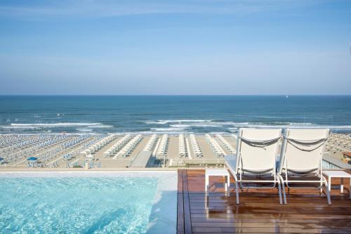 two chairs sitting on the deck of a resort with the beach at Grand Hotel Principe Di Piemonte in Viareggio