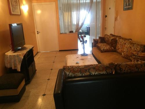 een woonkamer met een bank en een tv bij Room in Guest room - Property located in a quiet area close to the train station and town in Casablanca