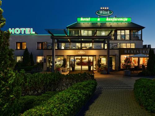 a hotel building with a lit up sign at night at Hotel Witek in Modlniczka