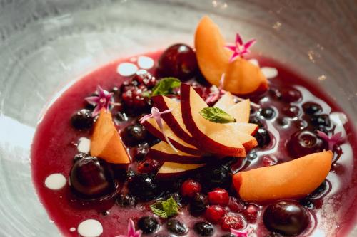a bowl of fruit and berries on a plate at Hunguest Hotel Sóstó in Nyíregyháza